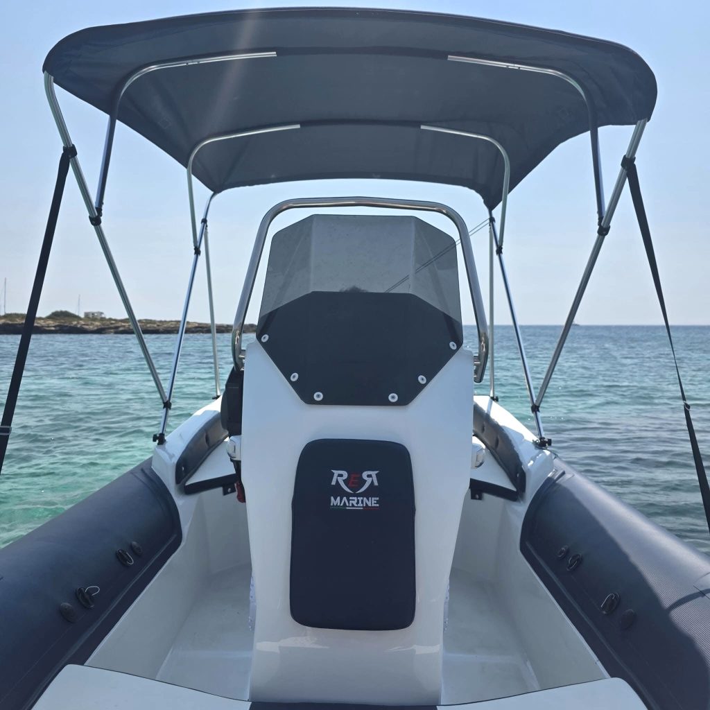 Consolle e tendalino di un gommone RER Marine in acqua, con la costa sullo sfondo