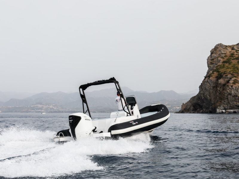 RER Marine 747 ripreso da poppa durante la navigazione vicino a una costa rocciosa.