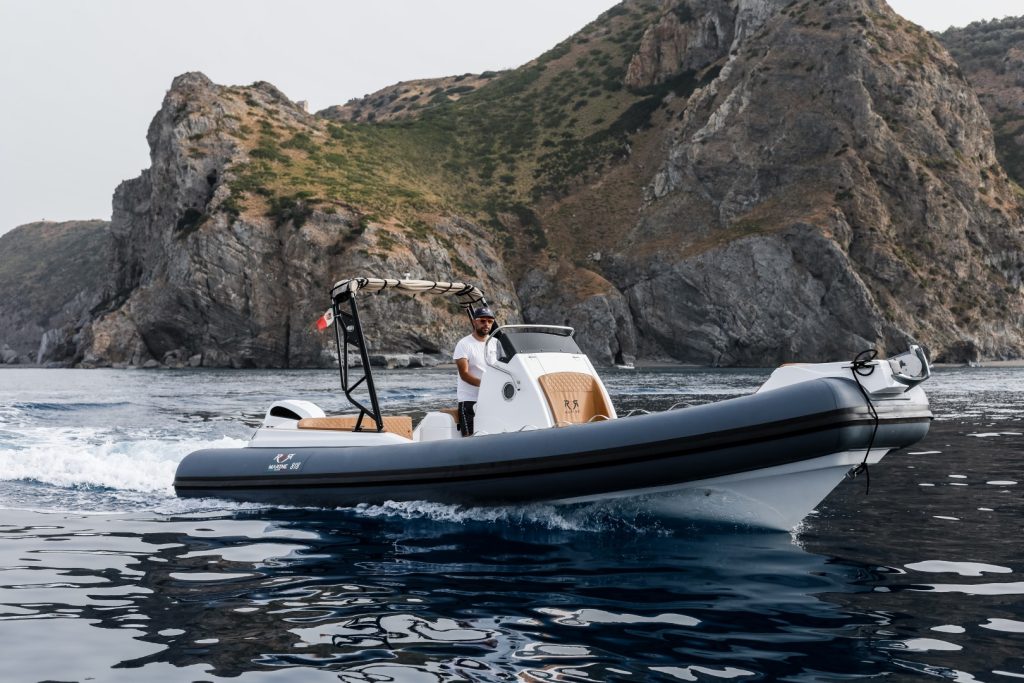 RER Marine 818 ripreso di tre quarti in navigazione davanti a una costa rocciosa.