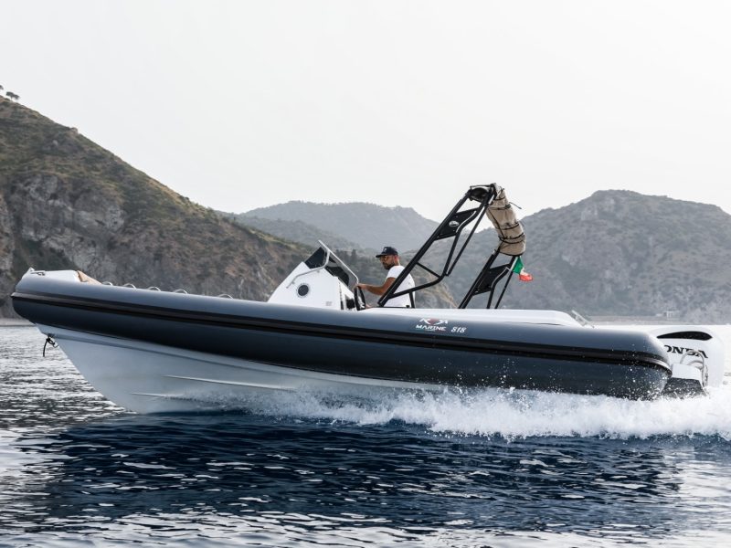 Vista laterale del RER Marine 818 in navigazione vicino a una costa rocciosa.