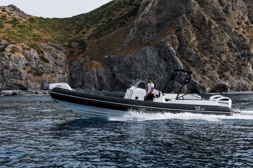 RER Marine 999 ripreso di fianco in navigazione davanti a una costa rocciosa.
